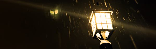 Orange tinted lantern with falling snow, camera lens toward sky.